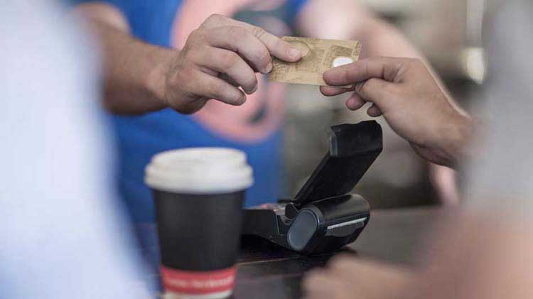 A teenager hands over a credit card as a payment for coffee.