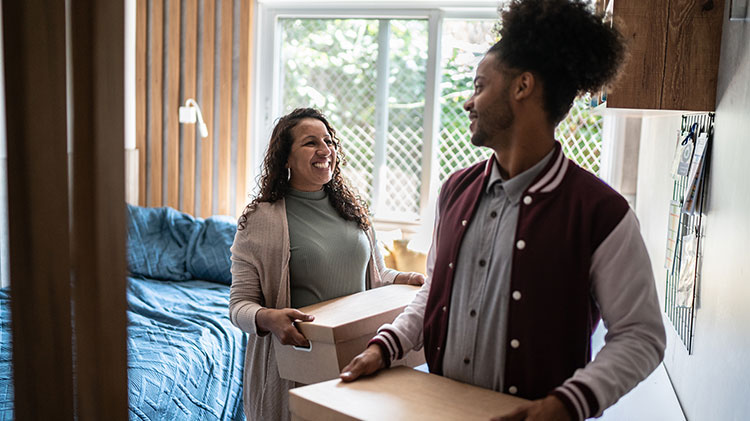 Mother helping son carry moving boxes to move out from parent’s home.