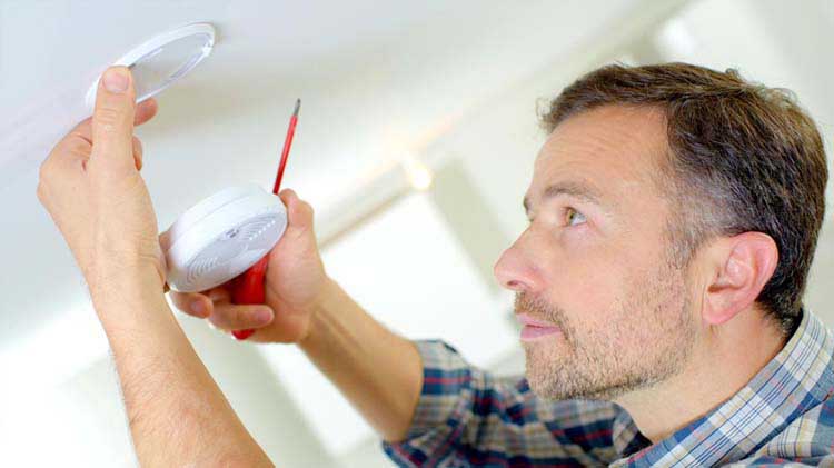 Man practicing fire safety and prevention by installing a smoke detector.