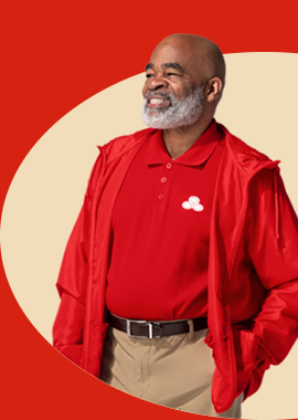 A bearded State Farm agent in red polo shirt and pullover smiles.