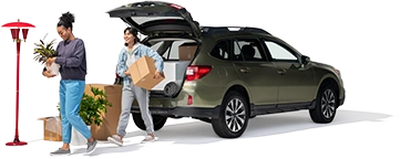 A mother and daughter unload plants and boxes from their SUV into their new home.