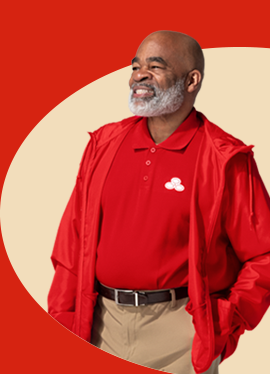 Un agente de State Farm con barba y vistiendo camiseta polo y chaqueta rojas aparece sonriendo.