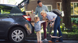 A family unloads groceries from the back of their SUV.