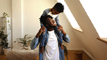 A son rides on his father’s shoulders in their condo.