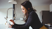 A woman in a black sweater checks the status of her claim on on her ipad.