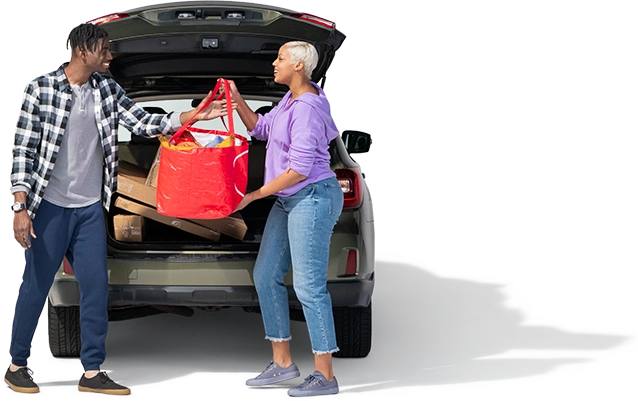 A mom hands a red grocery bag to her son happy she combined their home and auto policies to save money.