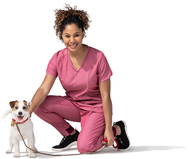 A kneeling woman in a pink outfit pets her terrier