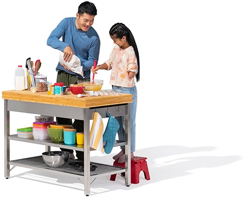 A father and daughter stir some batter at a free-standing kitchen counter