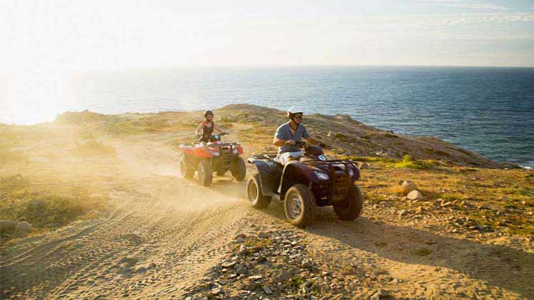 A pair kick up some dust on their ATVs.