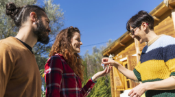 A smiling woman in glasses hands over the keys to a happy couple.