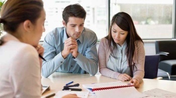 A couple review their insurance coverage while sitting at a desk with an agent.