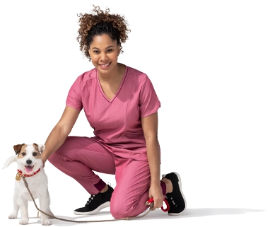 Una mujer arrodillada con ropa rosada acaricia a su perro terrier