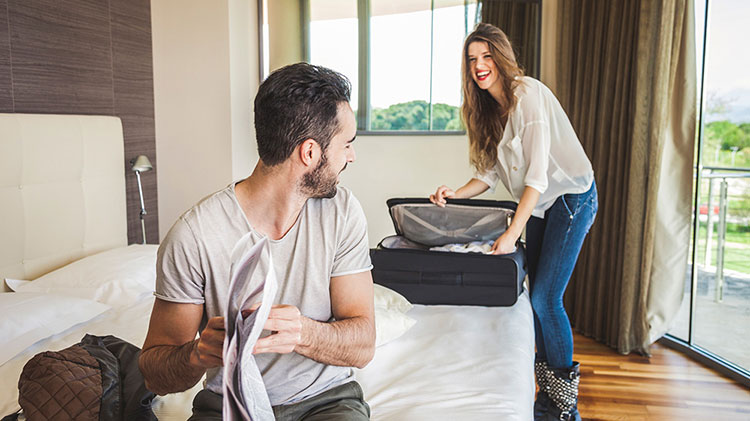 Una pareja desempaca dentro de su habitación de hotel.